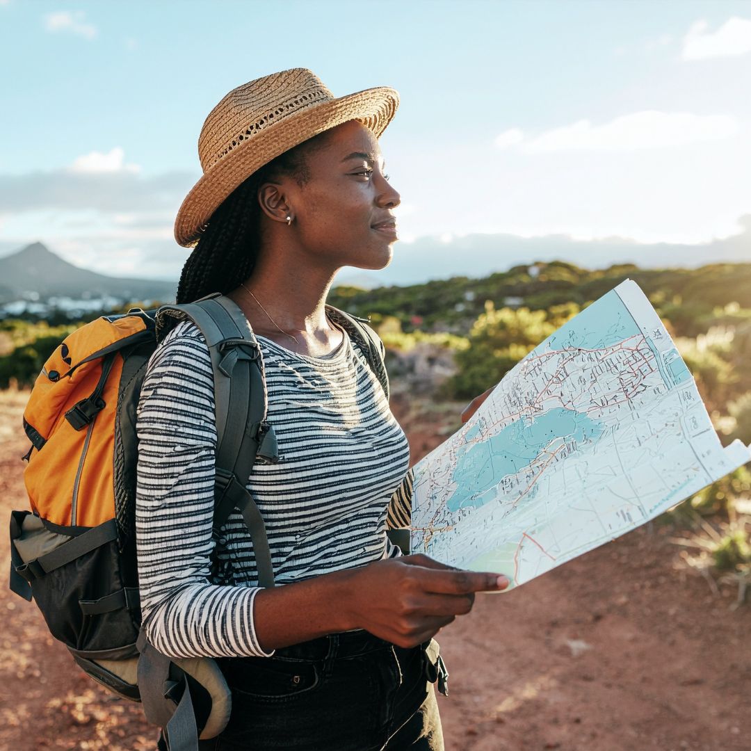 Woman with a backpack and hat holding a map in a natural setting